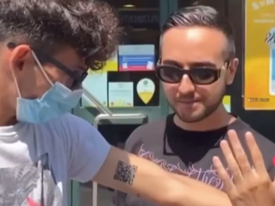 Un jeune homme se tatoue un pass sanitaire sur le bras